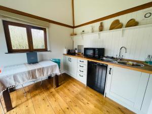 a kitchen with white cabinets and a table with a laptop on it at The Barn cottage with hot tub overlooking the lake in Ringmer
