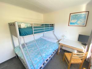 a bedroom with a bunk bed and a desk with a computer at Coastal Charm in Patons Rock in Rangihaeata