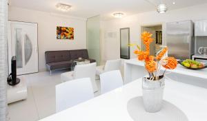 a white living room with white chairs and a vase with orange flowers at Apartments Šemper - HEATED POOL in Bol