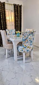 uma mesa de jantar e cadeiras com uma mesa branca em Mellow Homes 3 - Own compound em Kitengela 