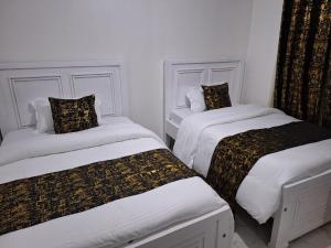 2 Betten in einem Zimmer mit weißen Wänden in der Unterkunft Mellow Homes 3 - Own compound in Kitengela 