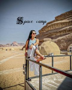 a woman sitting on a fence in the desert at Space camp in Wadi Rum