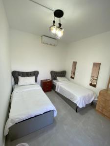 a bedroom with two beds and a chandelier at Tala bay apartments 2 bedroom in Aqaba