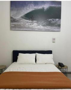 una cama con una foto de un surfista montando una ola en Low Cost Hoteles, en Piura