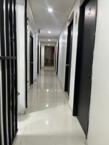 an empty hallway with black doors and white tile floors at Hostal Jireth in Floridablanca