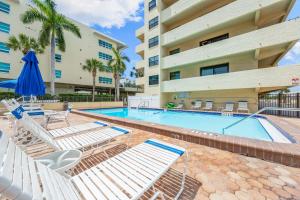 a swimming pool with lounge chairs and a building at Direct Beachfront Delight by Beachside Management in Siesta Key