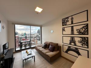 a living room with a couch and a large window at Five Stars Suites - Paris - Quito in Quito