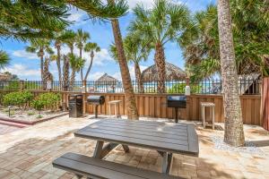 a patio with a picnic table and palm trees at Direct Beachfront Delight by Beachside Management in Siesta Key