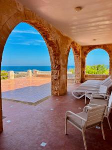 a patio with chairs and the ocean in the background at Villa Incina - Sea House in Polignano a Mare