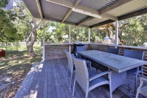 a wooden deck with a table and chairs on it at Beach Break at Hat Head - 22 Bay St - No Sheets or Towels Provided in Hat Head