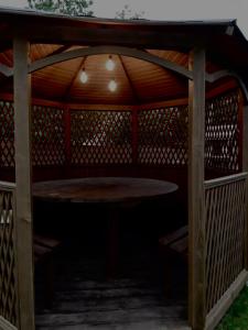 a wooden gazebo with a table in the shade at Four Seasons In Carpathians in Migovo