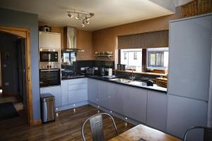 a large kitchen with white cabinets and appliances at Corncrake Cottage in Manish