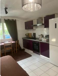 a kitchen with purple cabinets and a table and a refrigerator at Studio privatif in Goussainville