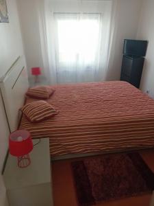 1 dormitorio con 1 cama con edredón rojo y ventana en Carolina do Mar, en Nazaré