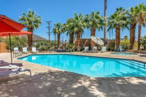 a swimming pool with palm trees and a red umbrella at Best Western Inn at Palm Springs in Palm Springs