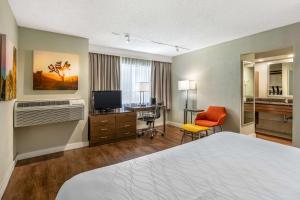Habitación de hotel con cama, escritorio y TV. en Best Western Inn at Palm Springs en Palm Springs