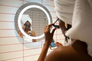 una mujer tomando una foto de sí misma en un espejo del baño en Radisson RED Hotel V&A Waterfront Cape Town, en Ciudad del Cabo