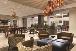 un vestíbulo con sillas y mesas y un bar en Embassy Suites by Hilton Bloomington/Minneapolis, en Bloomington
