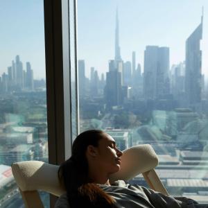 une femme assise dans une chaise donnant sur une fenêtre dans l'établissement SIRO One Za'abeel, à Dubaï