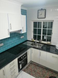 a kitchen with white cabinets and a clock on the wall at T1 with pool access concessiao Cabanas Tavira in Tavira