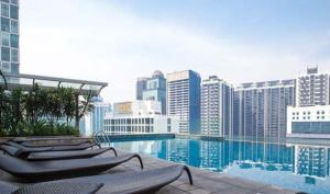 a swimming pool with lounge chairs and a city at Mont Kiara in Kuala Lumpur