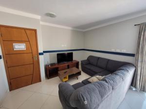 a living room with a couch and a television at Apartamento de frente para o mar, 3 quartos in Solemar