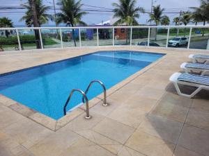 a swimming pool with two lounge chairs next to it at Apartamento de frente para o mar, 3 quartos in Solemar
