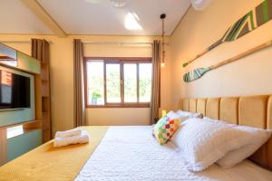 1 dormitorio con cama, ventana y TV en Lofts Corujinha Paraty, en Paraty