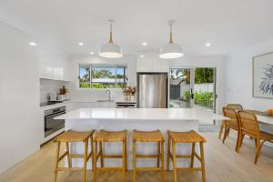 a kitchen with a large white island with bar stools at Aloka By Khove in Gold Coast
