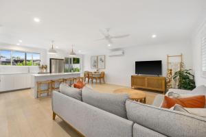 a living room with couches and a tv and a kitchen at Aloka By Khove in Gold Coast