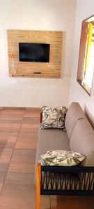 a living room with a couch and a tv on a wall at chalé Luizinho in Barra Grande