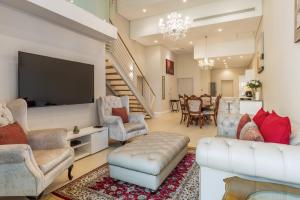 a living room with a tv and a couch and chairs at V&A Waterfront Luxury Apartments by McStay in Cape Town