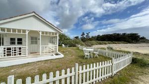 a white house with a fence and a table at MAISON SUR LA PLAGE avec VUE MER PANORAMIQUE in Le Martray
