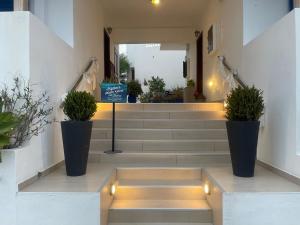 a lobby with stairs with potted plants and lights at Angelica's Deluxe Rooms in Adamas in Adamantas