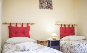 2 letti in una camera con cuscini rossi di Cifalino - Full Cozy Apartment with Wi-Fi in Catania a Catania