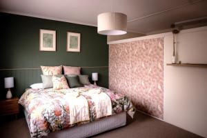 1 dormitorio con cama y pared verde en Twelve 30 - easy airport access, en Cambridge