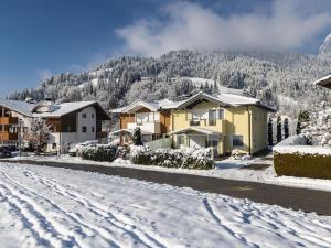 Une rue enneigée avec des maisons et une montagne dans l'établissement Ferienhaus Gartentraum 2, à Itter