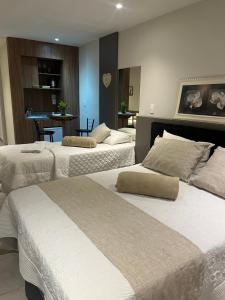 um quarto de hotel com três camas e uma mesa em Apart-hotel Nova Friburgo Com café da manhã em Nova Friburgo