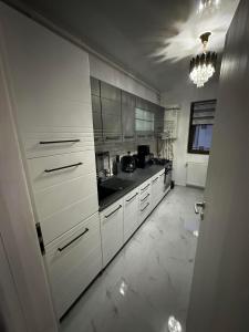 a large kitchen with white cabinets and a chandelier at Apartment Lux in Dobroeşti +13 photos