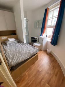 a bedroom with a bed and a desk and a window at Not very Quiet but best location in London