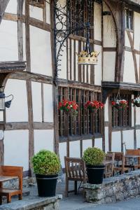 un edificio con bancos y macetas de flores. en The Crown Inn en Chiddingfold