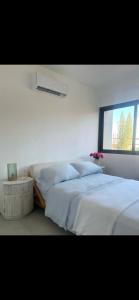 a white bedroom with two beds and a window at Santuario Home in Santo Domingo