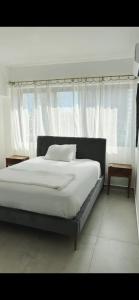 a bedroom with a bed with white sheets and a window at Santuario Home in Santo Domingo