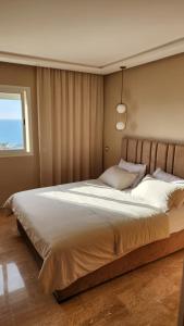 - un grand lit dans une chambre avec fenêtre dans l'établissement Beautiful beachfront apartment, à Rabat