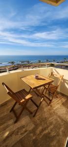 d'une table en bois et d'une chaise sur un balcon donnant sur la plage. dans l'établissement Beautiful beachfront apartment, à Rabat
