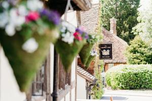 a bunch of flowers hanging off the side of a building at The Crown Inn in Chiddingfold