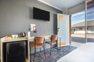 a room with a bed and a desk with two chairs at Nightcap at Horse & Jockey Hotel Warwick in Warwick