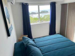 un letto blu in una stanza con finestra di Ocean View With Beach Club Access 12th Floor a Tárcoles