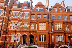 a large brick building with cars parked in front of it at Harrods Hideaway 3 Bedroom Flat in London