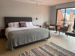 a bedroom with a large bed and a living room at Hotel Parque 97 in Bogotá